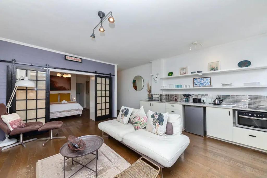 a living room with a white couch and a kitchen at Cosy 1BD APT in the Mother City in Cape Town