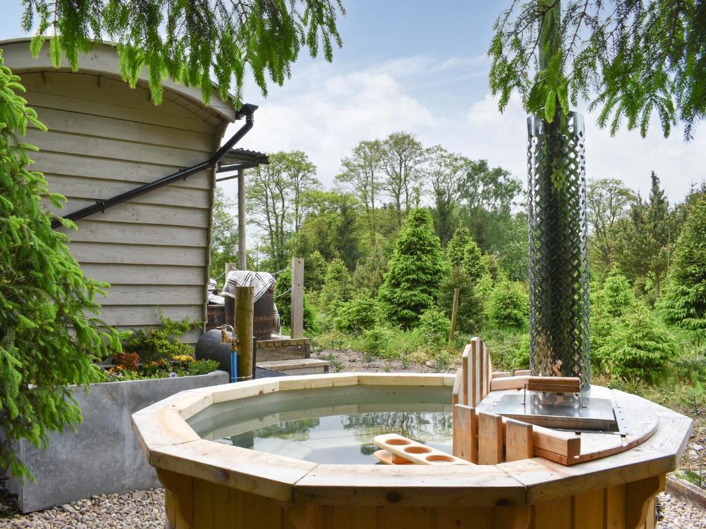 a hot tub in a garden with a tree at Spruce Shepherds Hut in Wilmslow