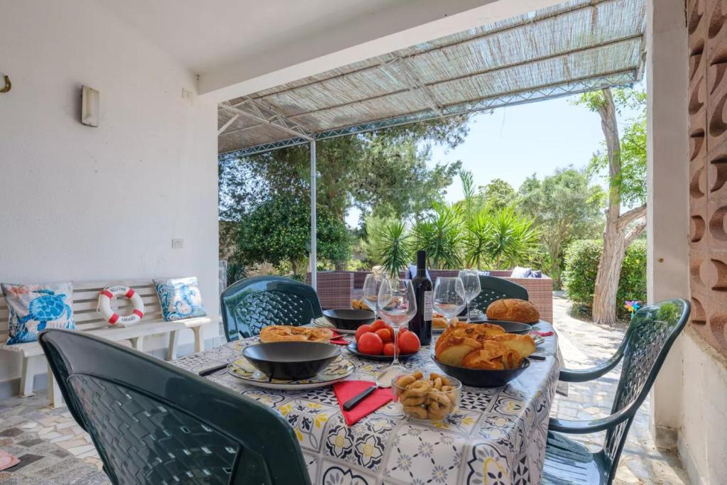 una mesa con comida y vino en un patio en Punta Prosciutto Sea View Facing the Sea With Air Conditioning, Parking And Wi-Fi, en Torre Lapillo