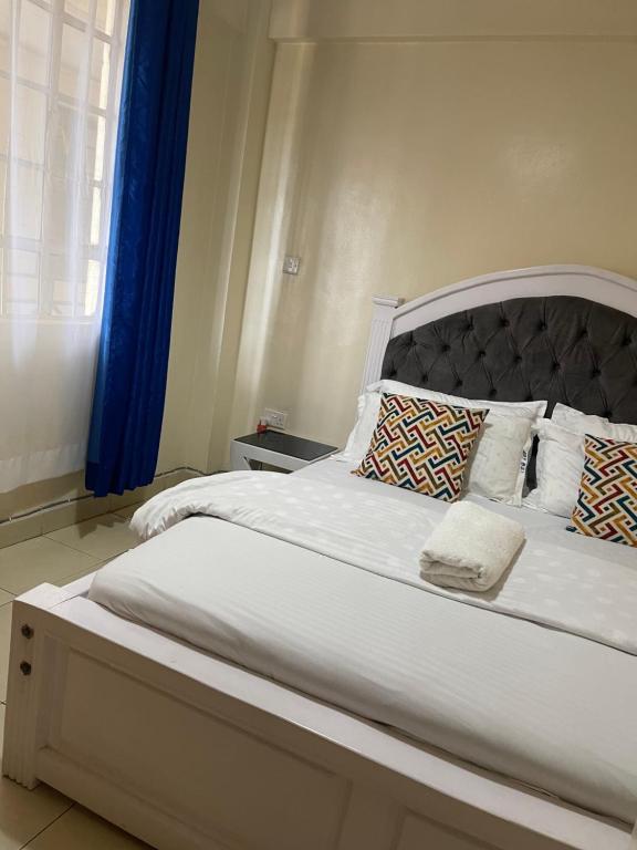 a bedroom with a large white bed with blue curtains at Homes by Essyruby in Nairobi