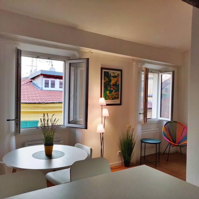 un salon avec une table, des chaises et des fenêtres dans l'établissement Au coeur du Vieux Nice: Charmant logement pour 4, à Nice