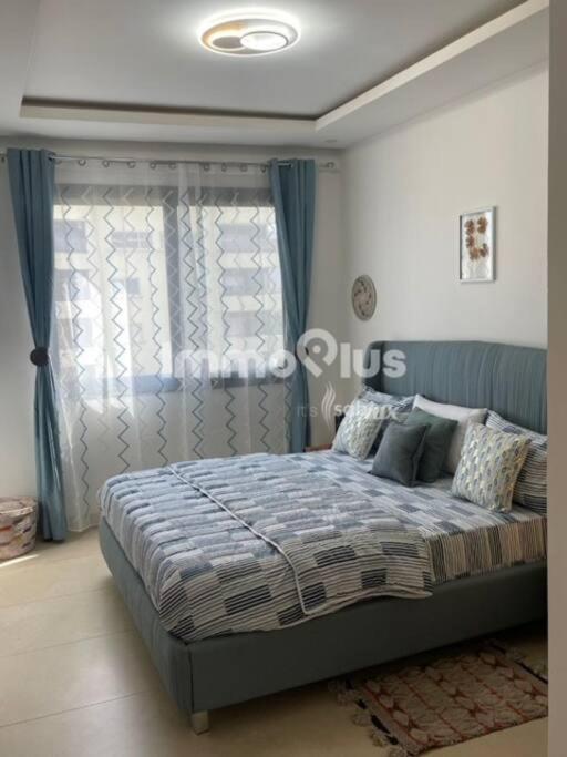 a bedroom with a large bed with blue curtains at Eden Home Point E Studio Neuf in Dakar