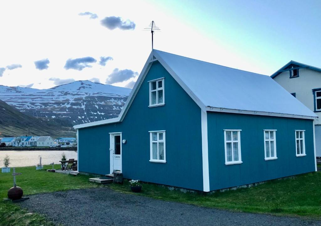 a blue house with a mountain in the background at Nýlenda in Seyðisfjörður