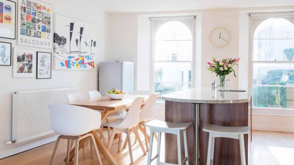 a kitchen with a wooden table and white chairs at Upper Seaton in Salcombe