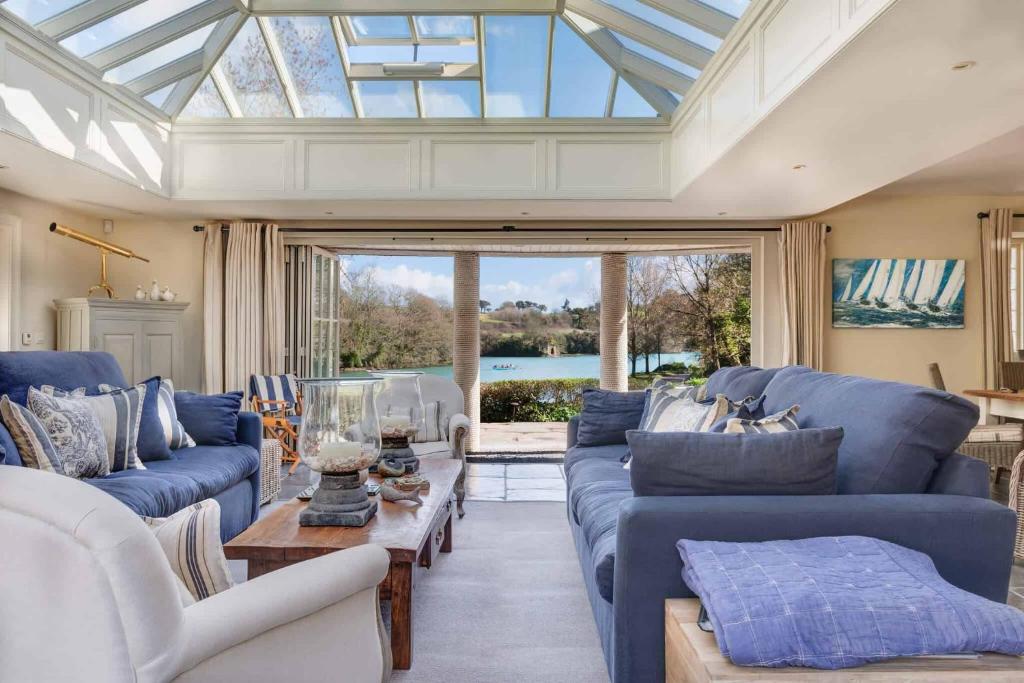 a living room with blue couches and a glass ceiling at Vine House in Salcombe