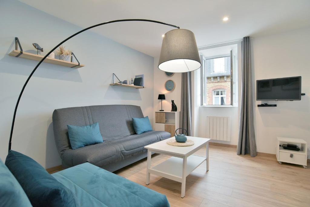 una sala de estar con un sofá y una mesa en L'Amanyn - Appartement proche plage, en Dinard