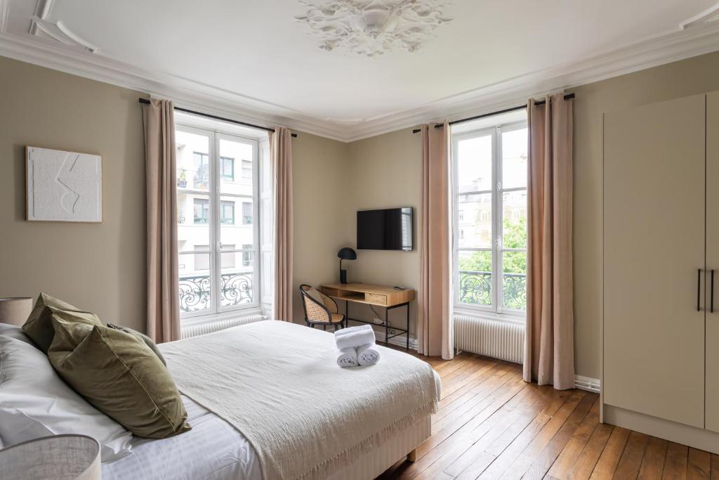 a bedroom with a bed and a table and windows at Le Goya - Appartement 4 chambres centre ville de Rennes in Rennes
