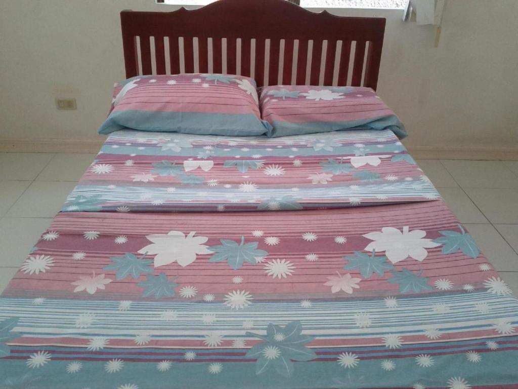 ein Bett mit rosa und blauer Bettdecke darauf in der Unterkunft Sea Apartment-Pinca in Manila