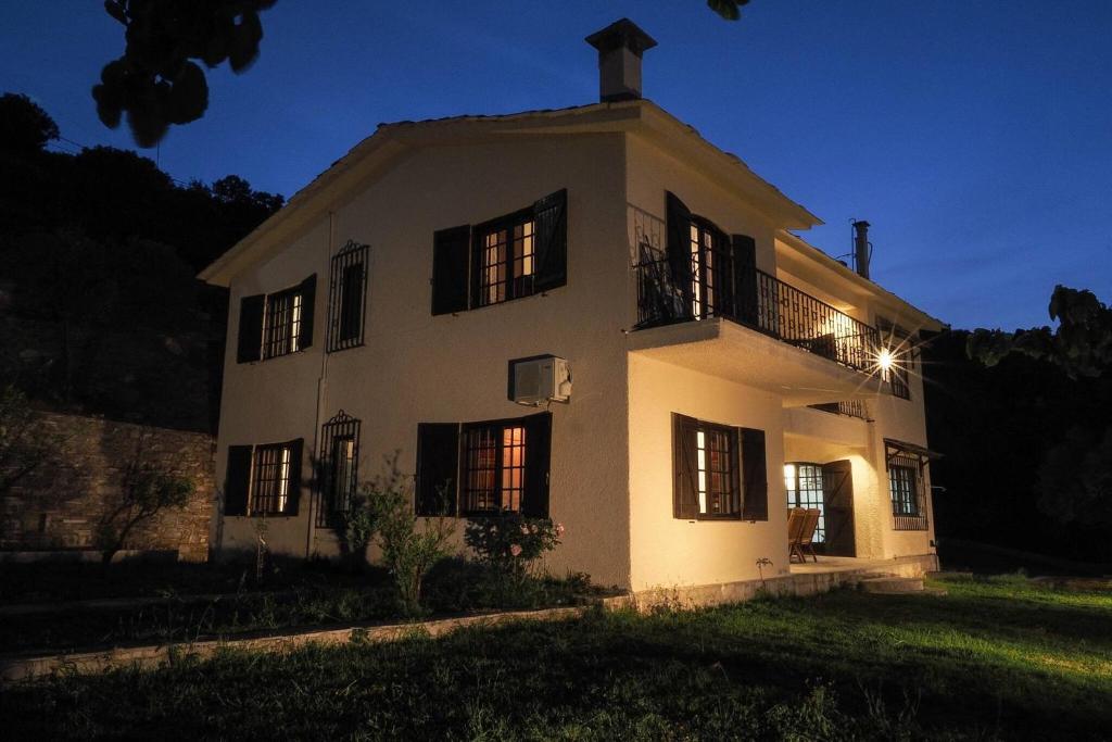 a white house at night with the lights on at Sonia Rustic Mansion - 5bd 30 Sec Walk To Beach in Agioi Apostoli