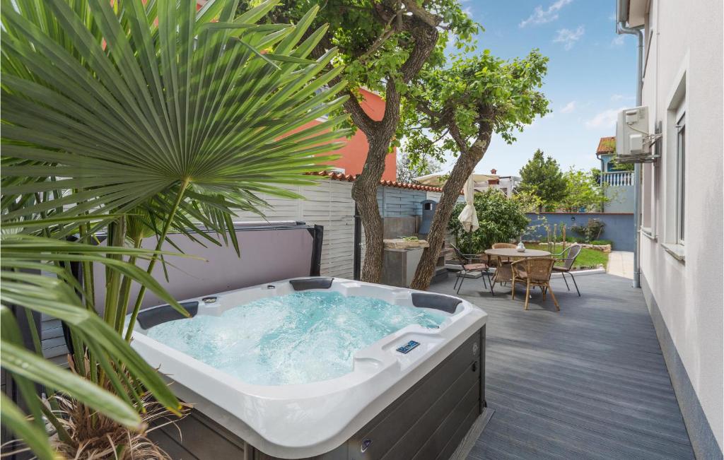 a hot tub on a patio with a plant at Nice Home In Barbariga With 3 Bedrooms, Wifi And Jacuzzi in Barbariga