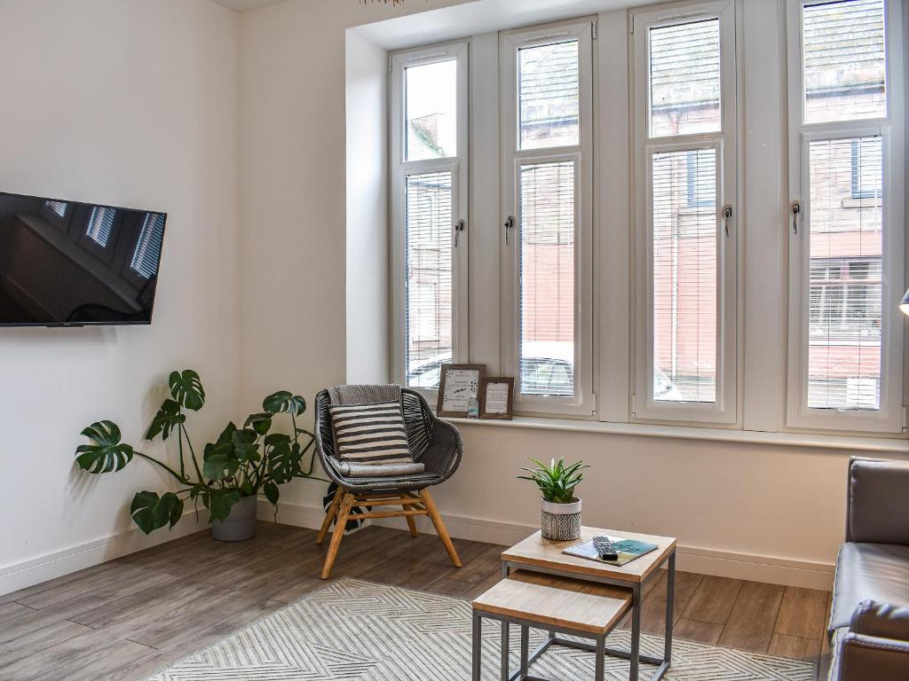 a living room with a chair and a couch and windows at Apartment 1 - Ukc6766 in Arbroath