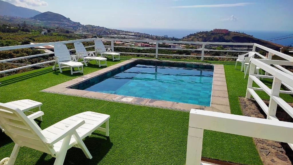 a swimming pool with white chairs and a table at Estancia Cecilia in La Orotava