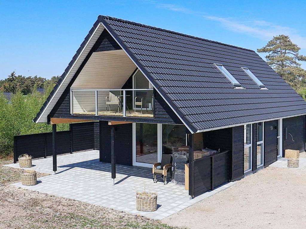 a house with a black roof with a patio at Holiday home Læsø II in Læsø