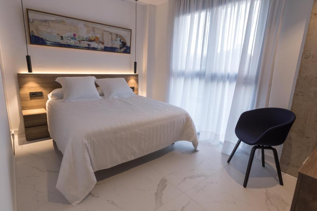 a bedroom with a large bed and a chair at RÍOS SUITES Tudela in Tudela