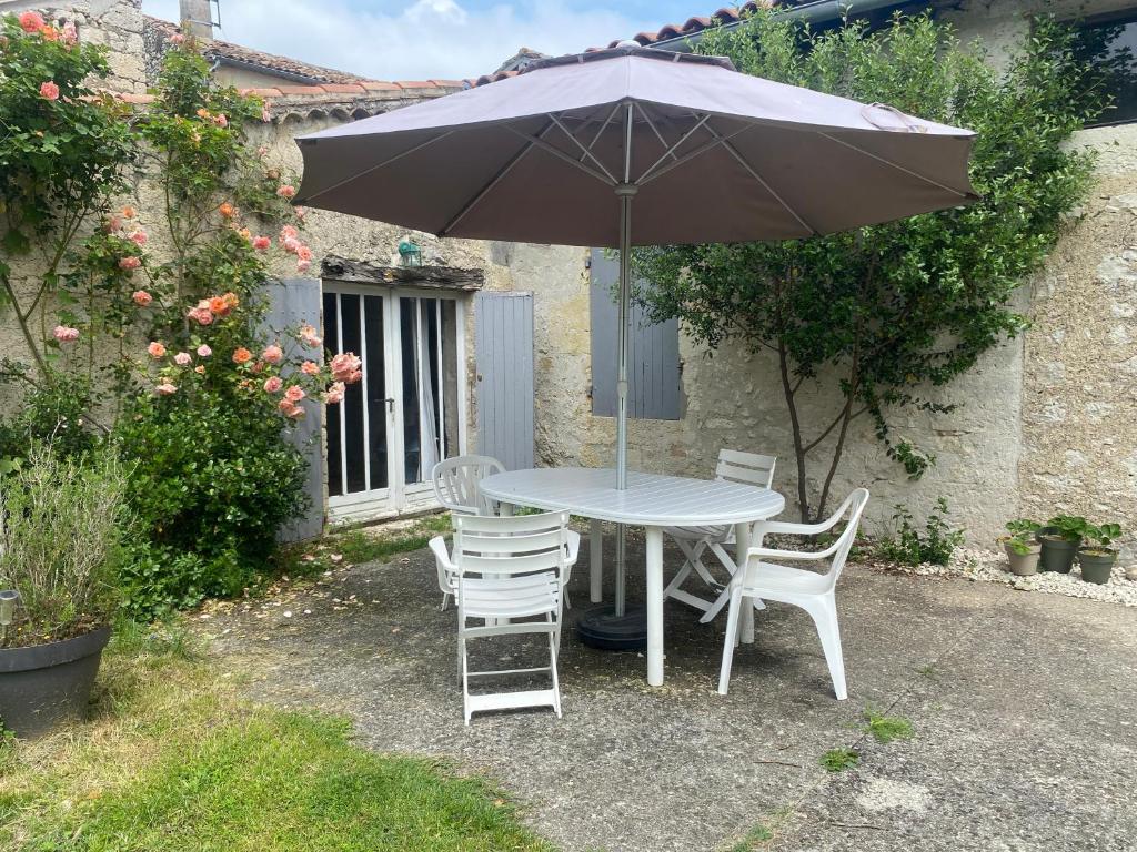 a table and chairs with an umbrella in a yard at Studio 1 lit 140cm et 1 lit 90cm in Saint-Mézard