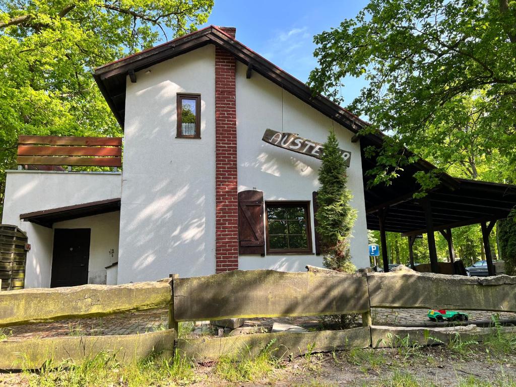 a small white house with a fence in front of it at Austeria Przyjezierze in Pojezierze