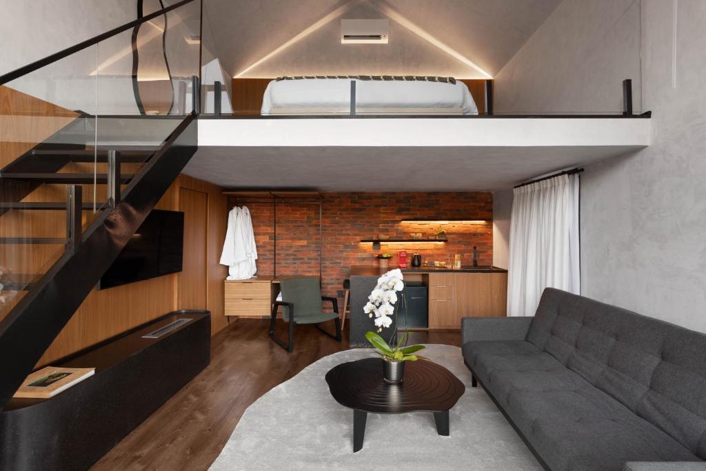 a living room with a couch and a loft bed at NÖR Hotel & SPA in São Roque