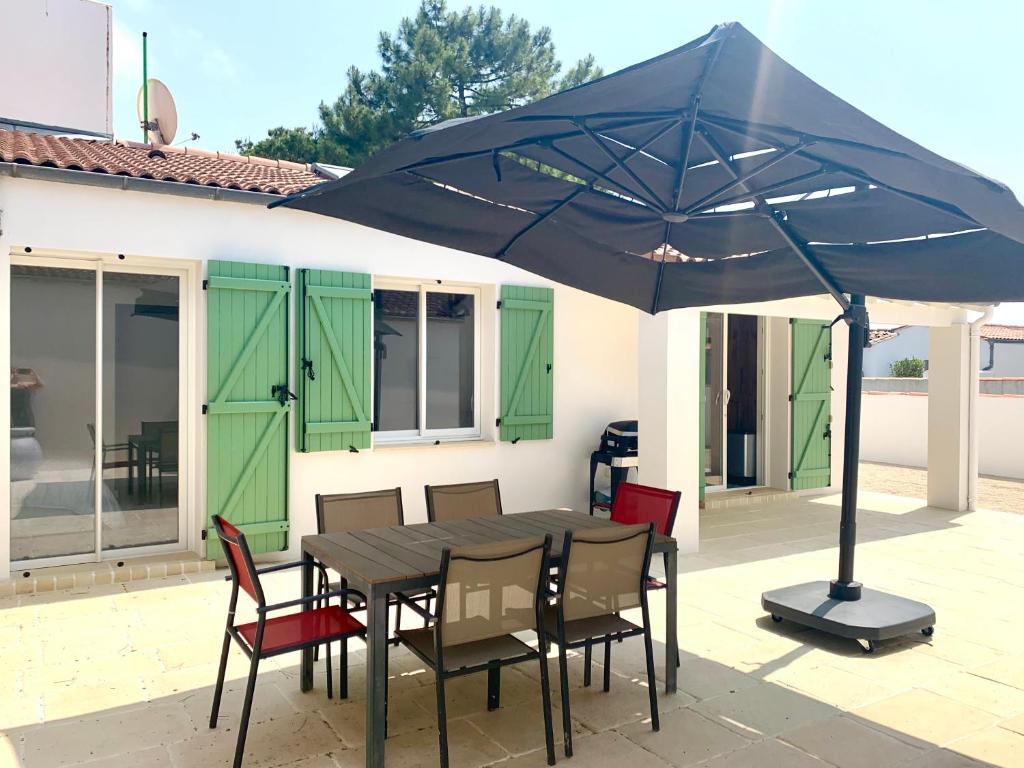 a table and chairs under a blue umbrella on a patio at CAPUCINE Jolie maison proche Plage in La Couarde-sur-Mer