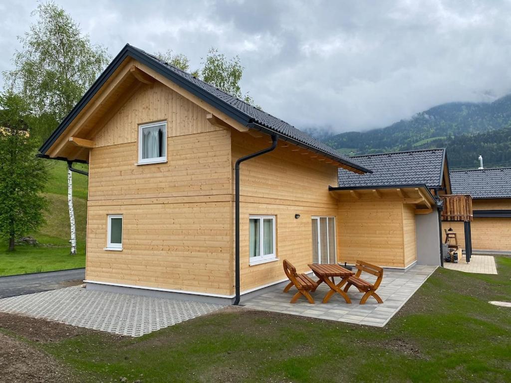 ein Haus mit zwei Stühlen und einem Tisch davor in der Unterkunft Felsenfest Cottage in Kötschach