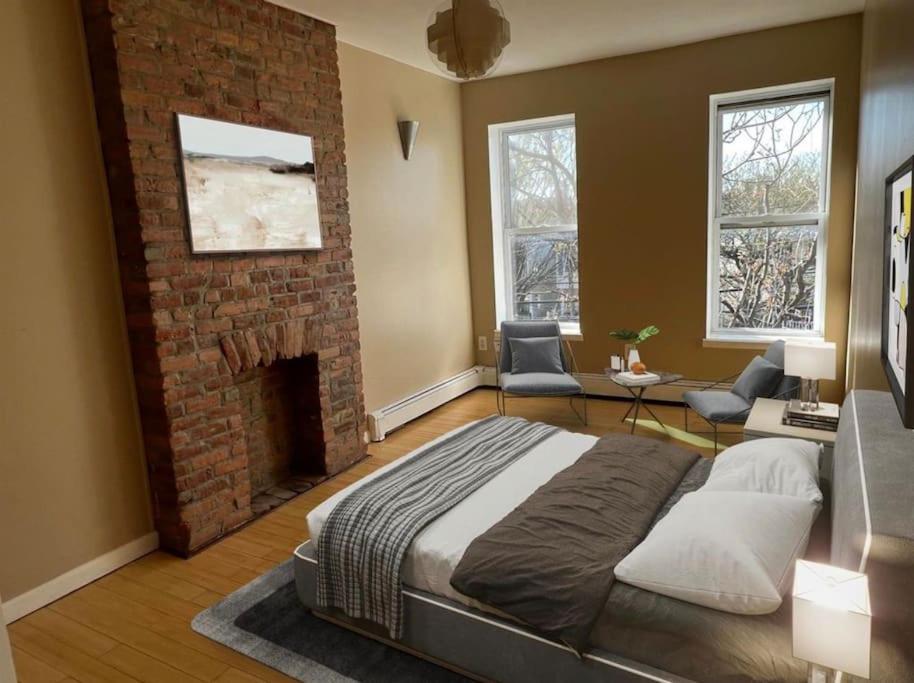 a bedroom with a large bed and a brick fireplace at Liberty Dream - 20 min to NYC in Jersey City