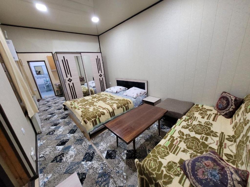 a hotel room with two beds and a table at UZUMZOR HOUSE in Aktepa-Chigatay