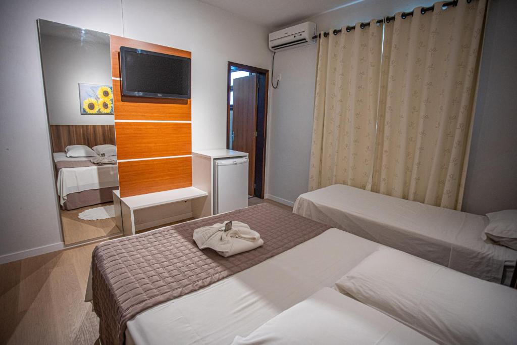 a hotel room with two beds and a television at Hotel Raul's in Gaspar