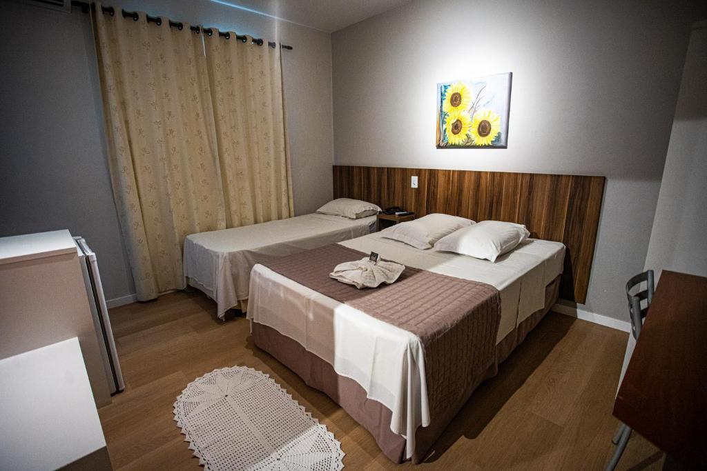 a hotel room with two beds and a painting on the wall at Hotel Raul's in Gaspar