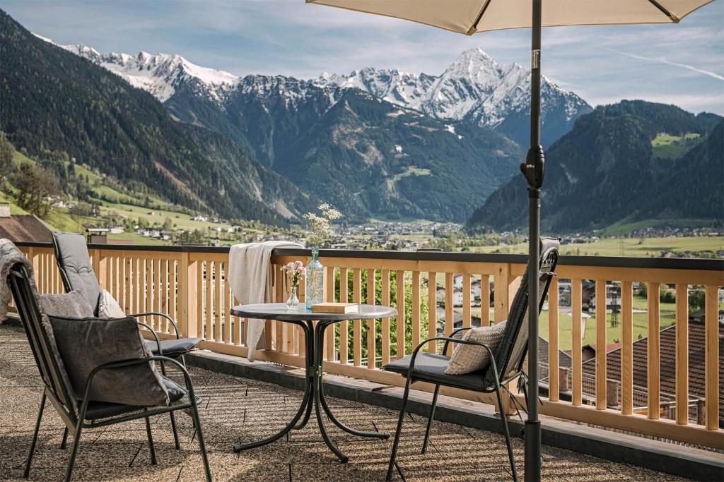 a table and chairs on a balcony with mountains at Apart. Mountainlovers in Hainzenberg