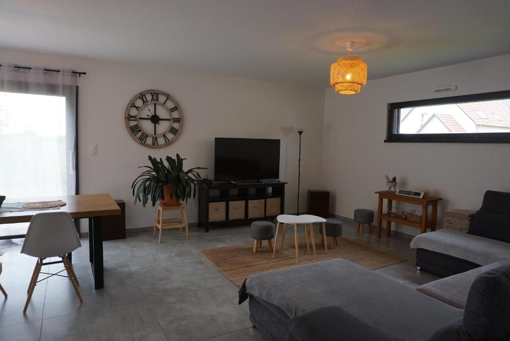 uma sala de estar com um sofá e um relógio na parede em Entre vignes et châteaux - charmante maison au calme, idéale pour famille ou entre amis - parking gratuit em Dieffenthal