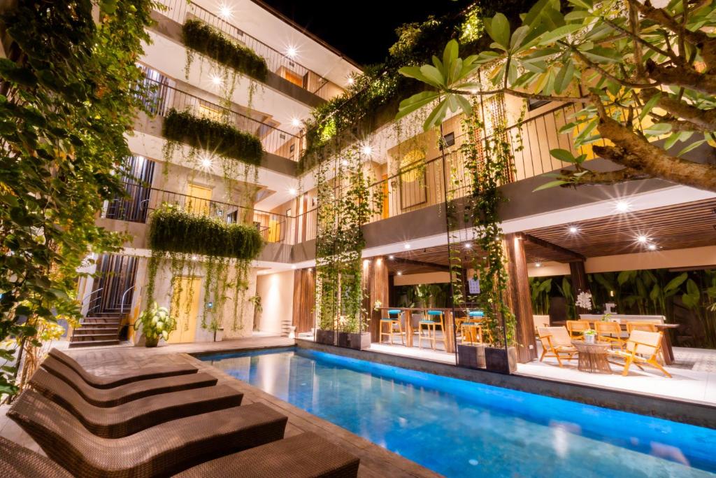 a hotel with a swimming pool in front of a building at Tanaga CoLiving in Seminyak