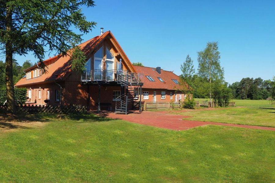 una casa grande con techo de gambrel en un campo en Schröderhof en Unterlüß