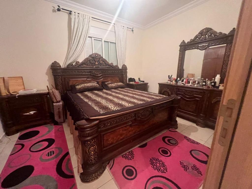 ein Schlafzimmer mit einem großen Holzbett und einem Spiegel in der Unterkunft مدينة أصيلة قرب طريق السيار طنجة المغرب in Asilah