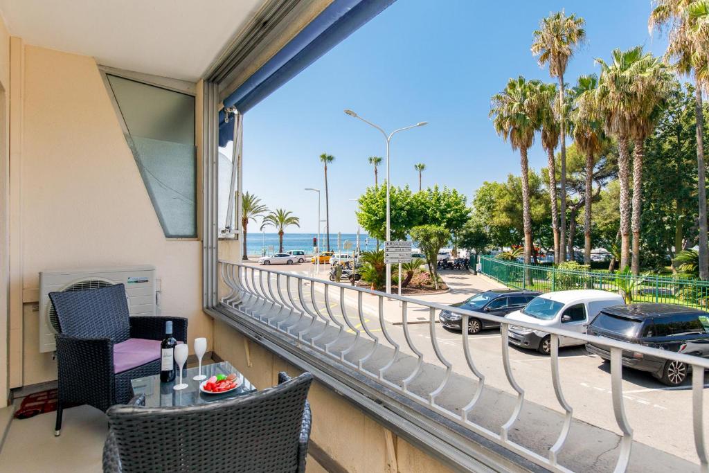 - un balcon avec vue sur la plage et les voitures dans l'établissement Les 3 Palmiers YourHostHelper, à Cannes