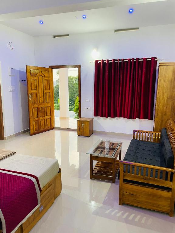 um quarto com uma cama, um sofá e uma mesa em Flowers Villa em Ambalavayal