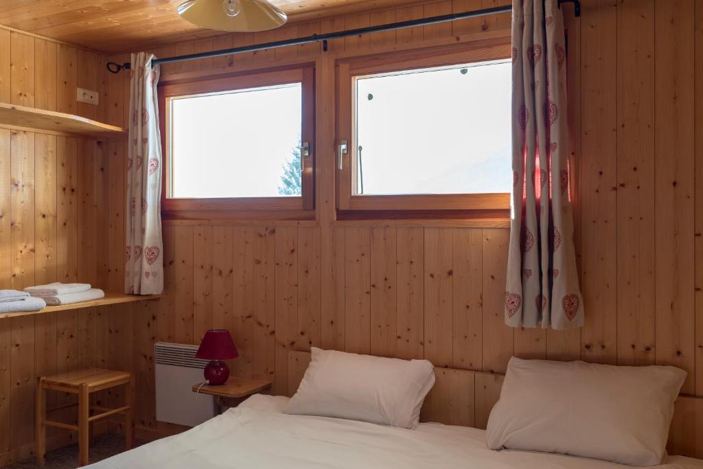 a bedroom with a bed and two windows at Chalet Le Lapye in Les Gets