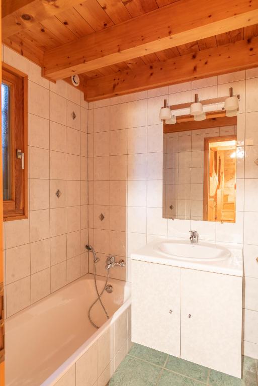 a bathroom with a tub and a sink at Chalet Le Lapye in Les Gets