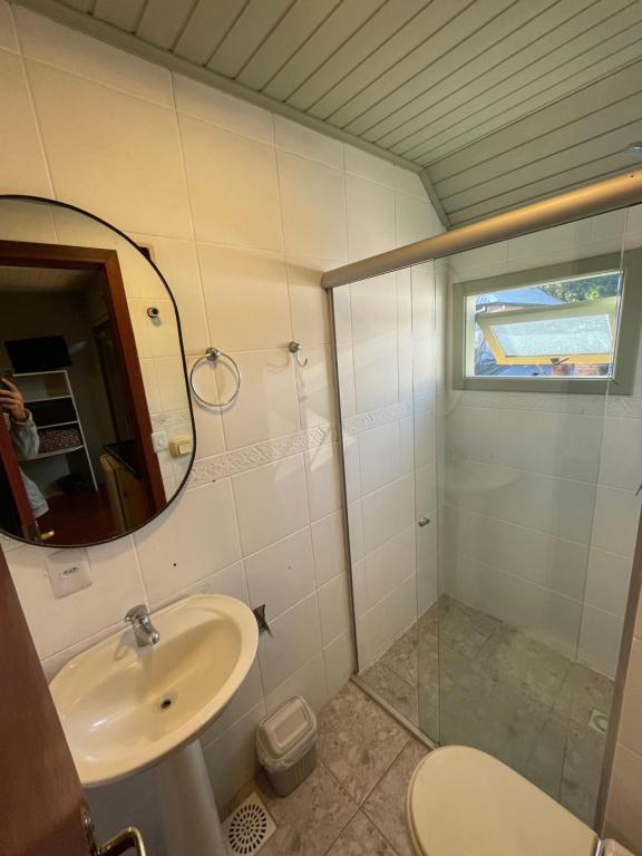 a bathroom with a sink and a mirror and a toilet at Pousada do Mel in Gramado