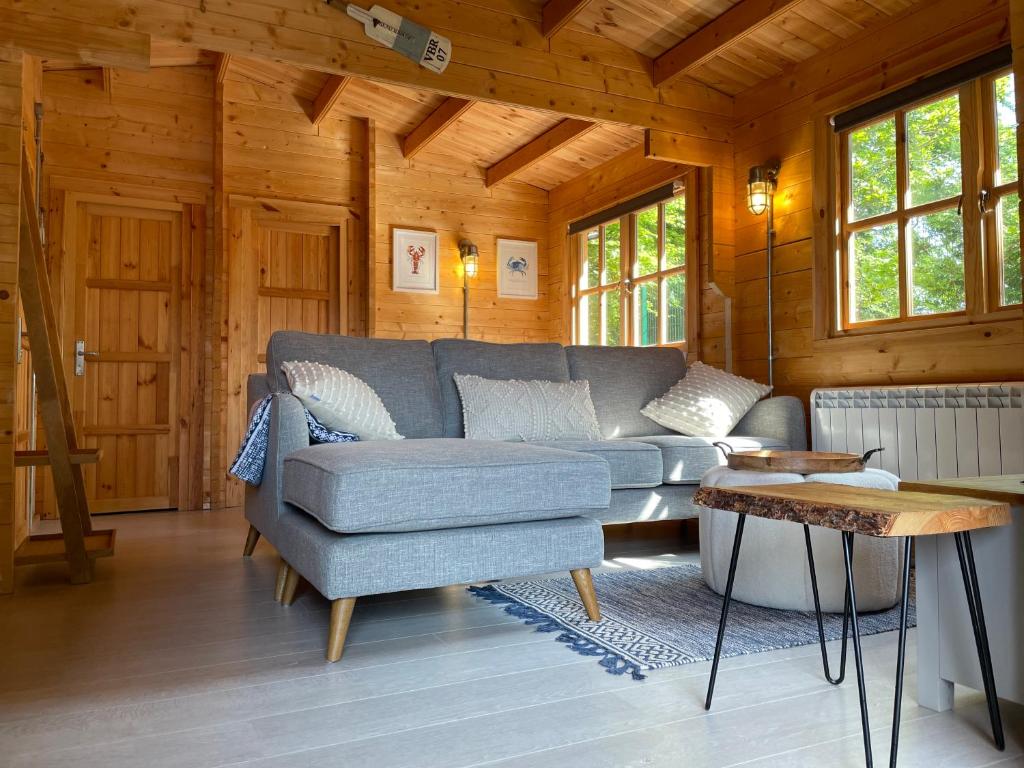 een woonkamer met een bank en een stoel bij O Dan Y Coed Swedish Log Cabin with New 2024 Wood Fired Hot Tub in Chwilog