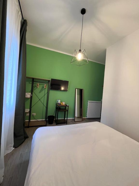 a bedroom with a white bed and a green wall at A Pisa con amore in Pisa