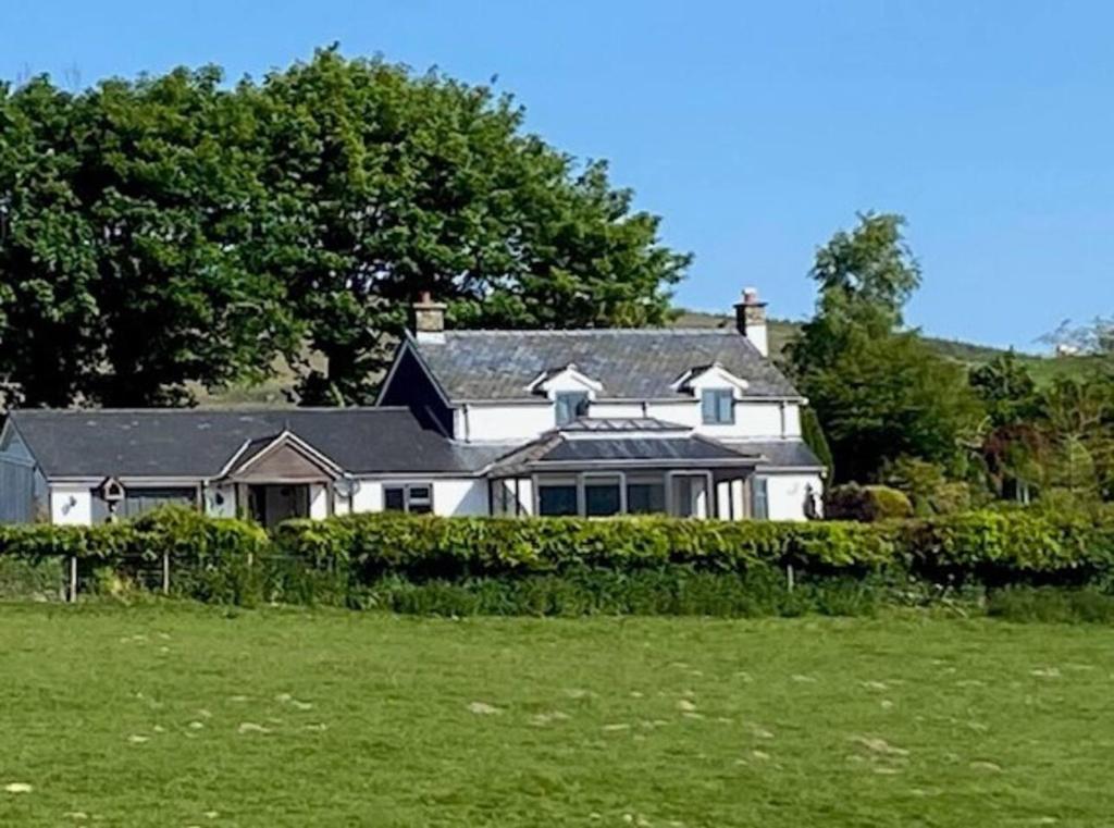 una casa blanca con un campo verde delante de ella en Tranquil 3-Bed Cottage Near Lake Vyrnwy, en Hirnant