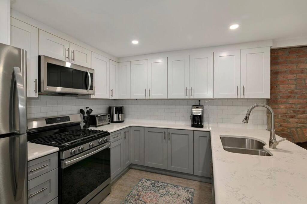 a kitchen with white cabinets and stainless steel appliances at Sweet Home - 20 minutes to NYC in Jersey City