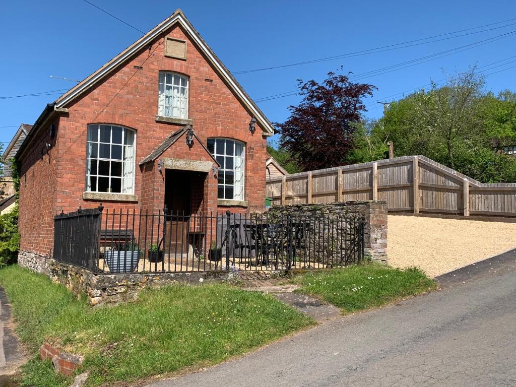 an old red brick house with a fence at St Milburga Chapel 