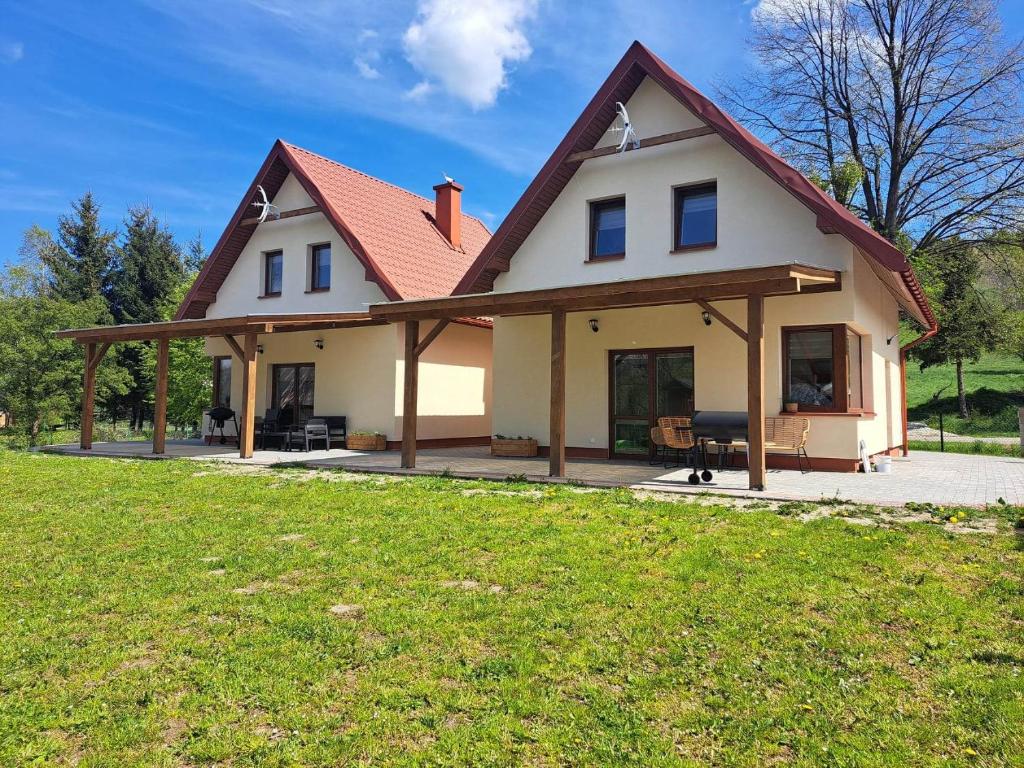 duży biały dom z czerwonym dachem w obiekcie Słoneczna Sielanka domki w Bieszczadach w mieście Ustrzyki Dolne