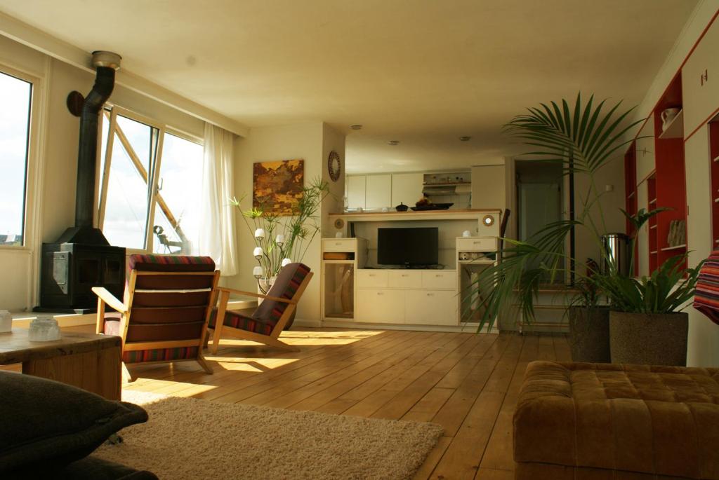 a living room with a couch and a table and a kitchen at Ecostay de IJsvogel in Kampen