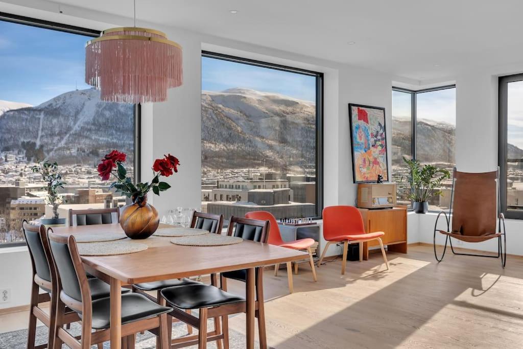 a dining room with a table and chairs and windows at Luxury apartment in the center of Tromsø in Tromsø