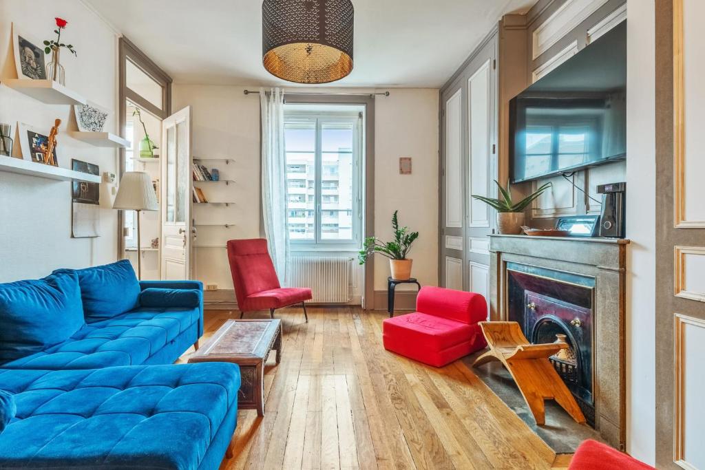 - un salon avec un canapé bleu et des fauteuils rouges dans l'établissement Appartement Merisier - Welkeys, à Villeurbanne