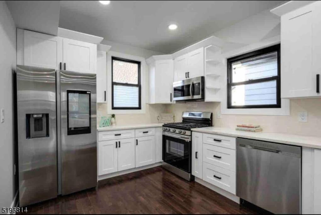 una cocina con armarios blancos y electrodomésticos de acero inoxidable en Secret Escape - 20 min from NYC N 2 en Jersey City