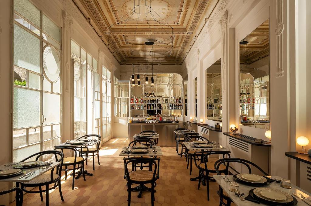 ein Restaurant mit Tischen und Stühlen in einem Zimmer mit Fenstern in der Unterkunft Artemisia Domus - Giardino in Neapel