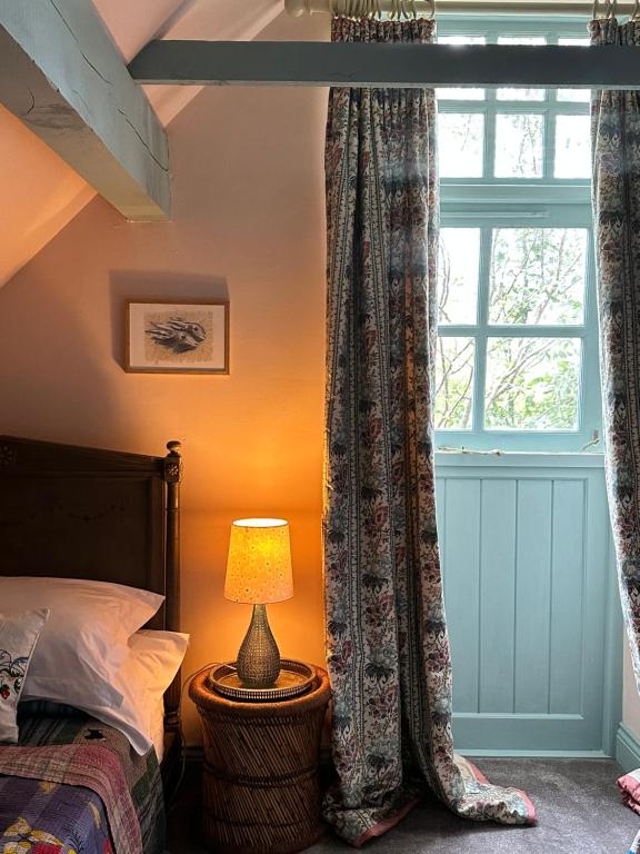 a bedroom with a bed and a window with curtains at Peaceful cottage with private garden in Hailsham