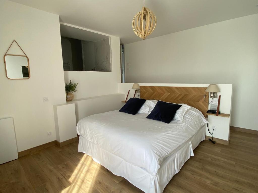 um quarto com uma cama com lençóis brancos e almofadas azuis em LA TOUR AUX CRABES près de la plage em Dieppe